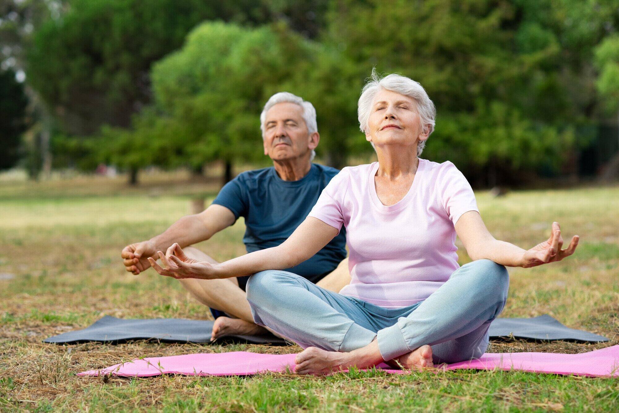 Senior couple practicing yoga outdoors